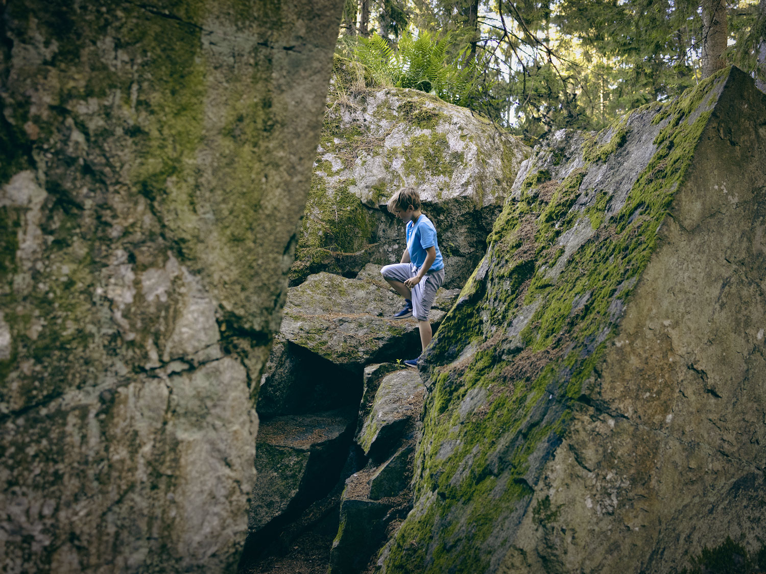 En pojke klättrar bland stora stenblock