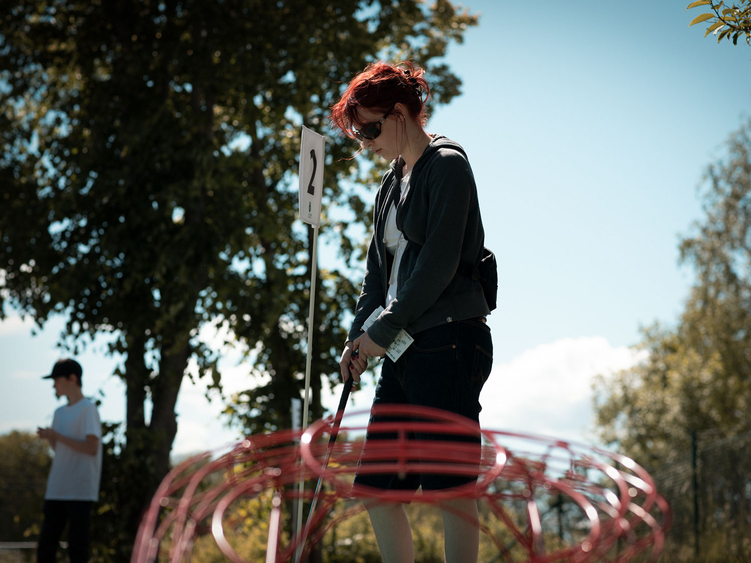 En tjej håller i en golfklubba intill en minigolfbana. 