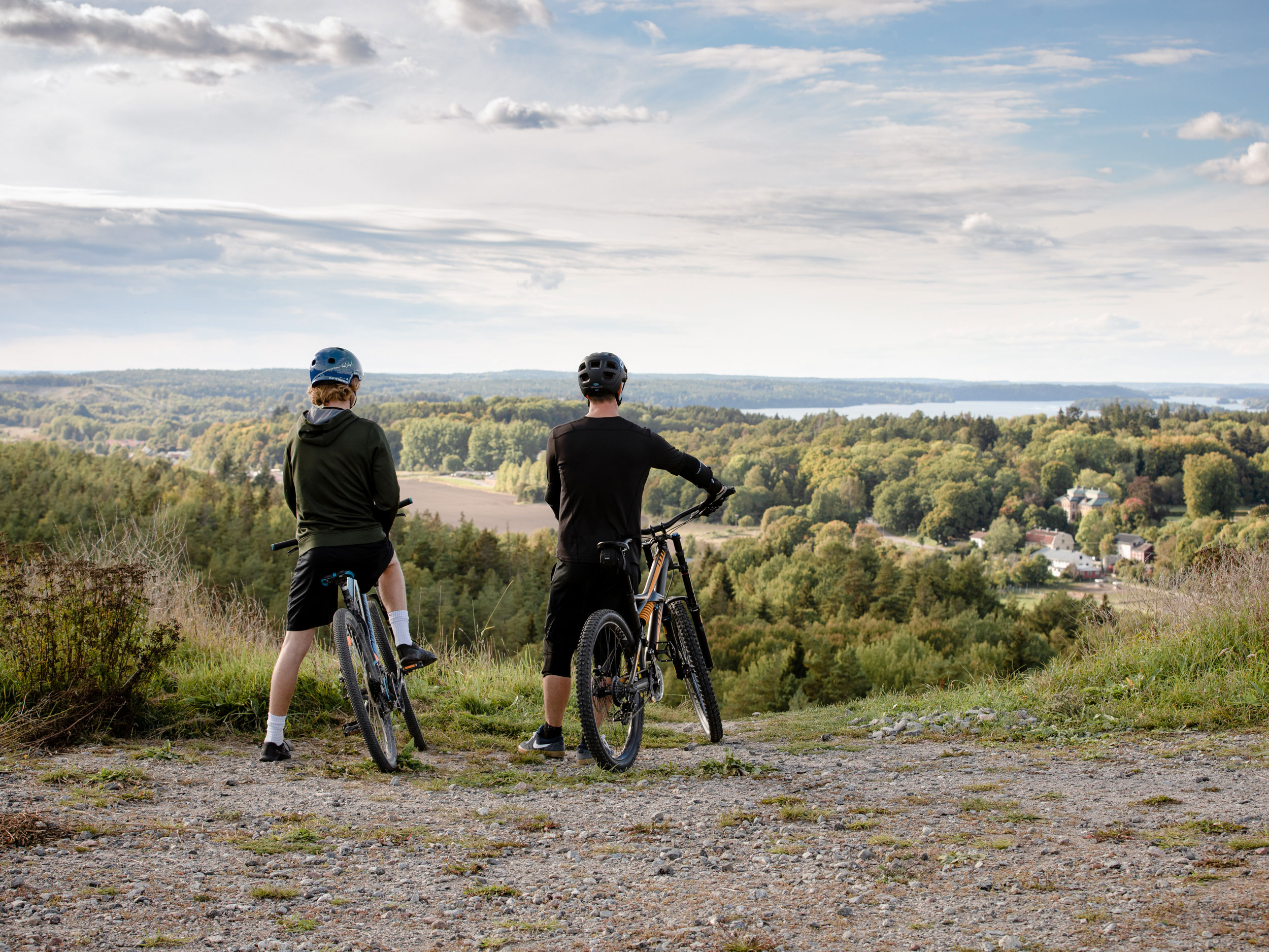 Två män står på en höjd med sina cyklar och tittar ut över landskapet.