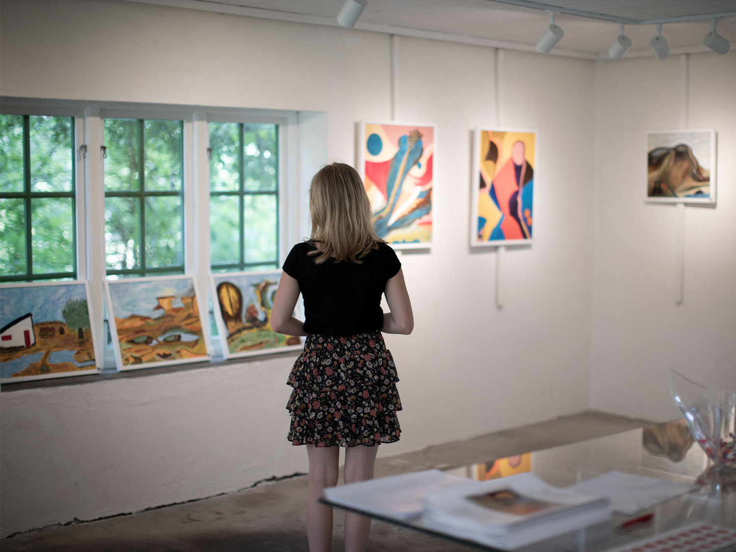 En flicka står i ett galleri där det hänger konst på väggarna.