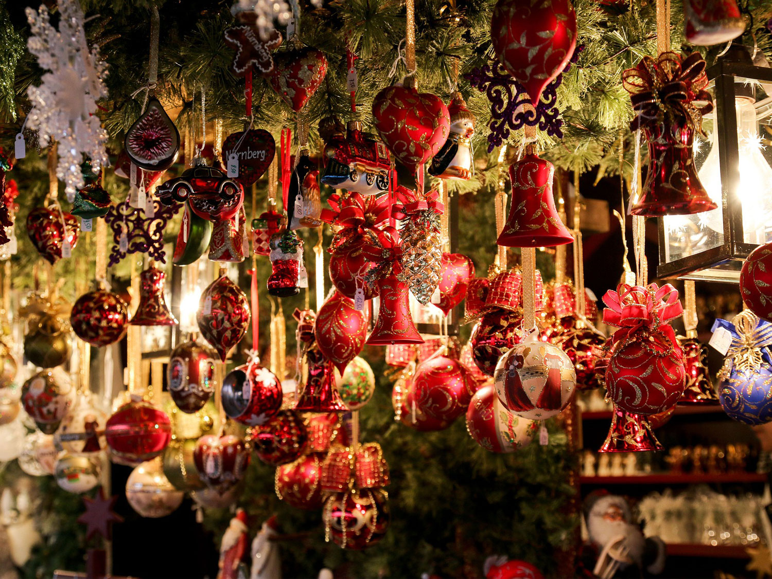 Röda julkulor i olika former hänger från ett tak som är täckt av granris.