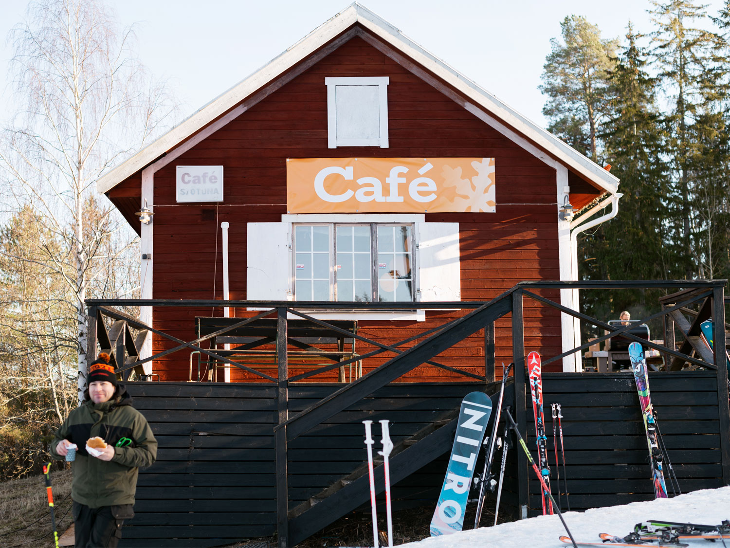 En röd trästuga med skidor lutade mot väggen. På en skylt står det café.