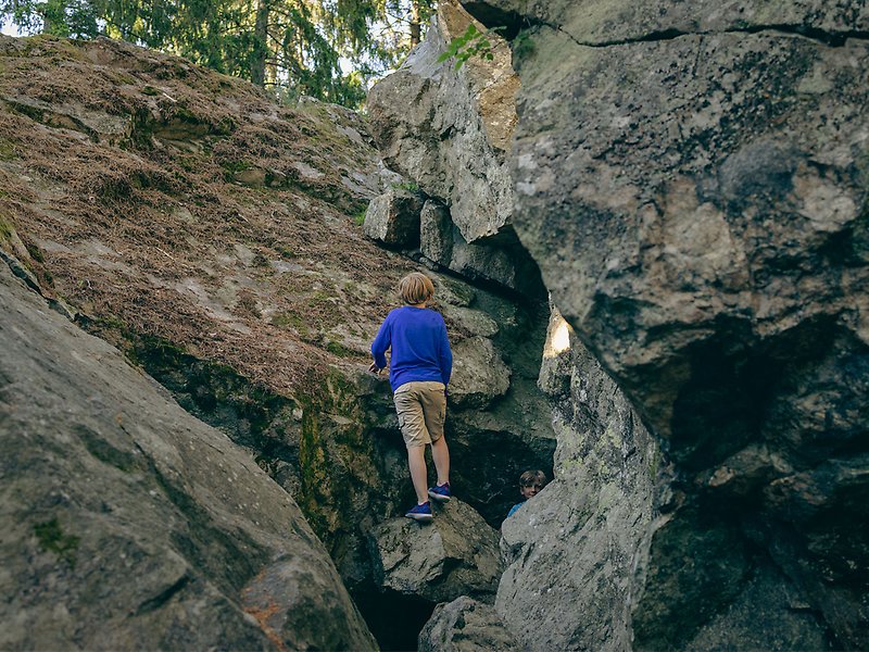 En pojke klättrar upp för en väldigt stor sten