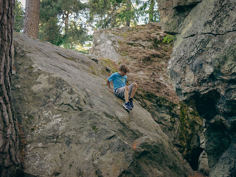 En pojke sitter på en väldigt stor sten