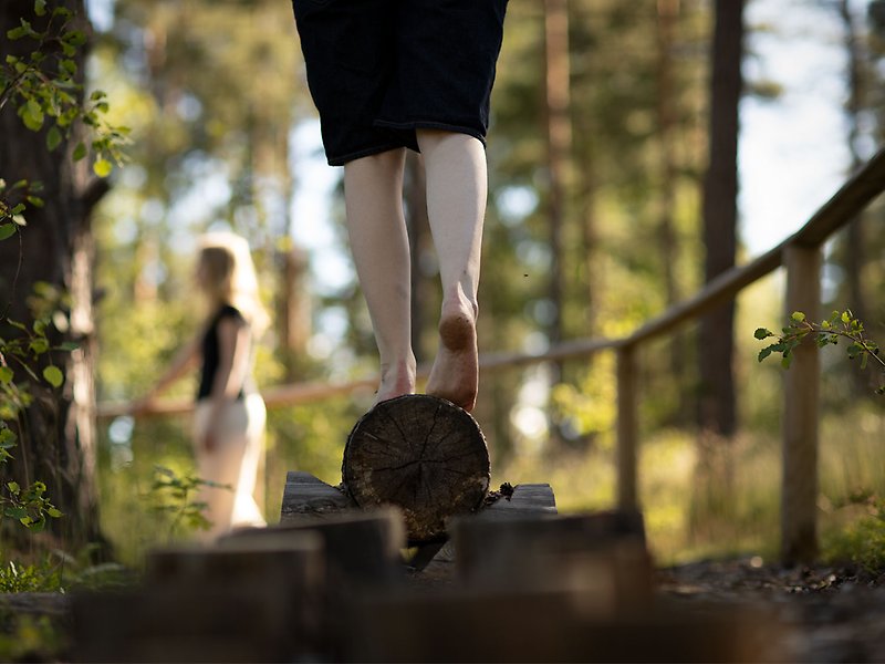 Närbild på ett par barfota fötter som går på en stock. 