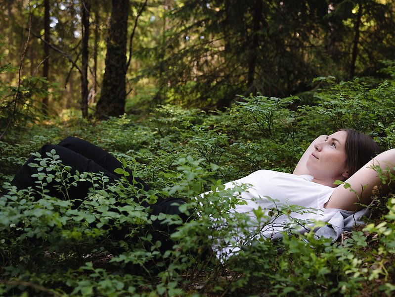 En kvinna ligger på marken i en skog