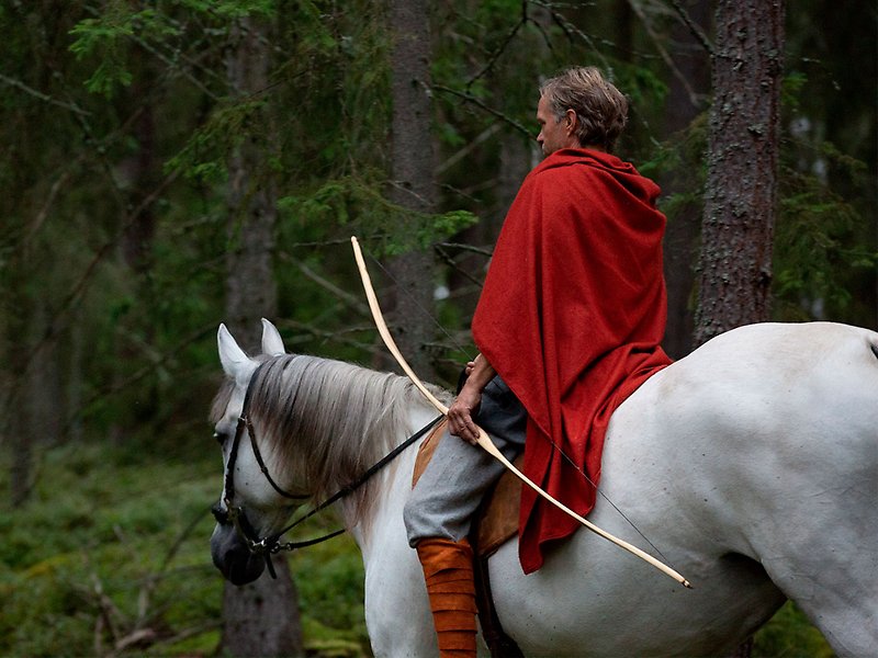 En man rider på en häst i skogen.