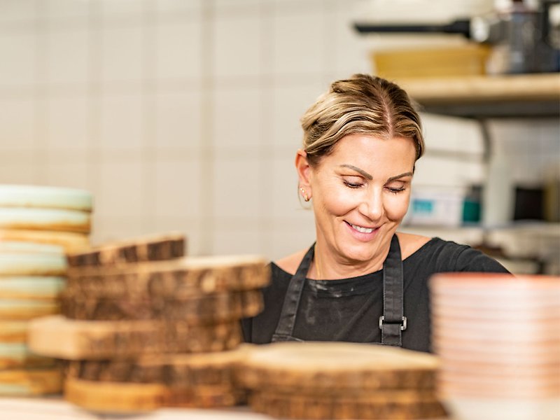 En kvinna står bakom brödskivor och ler.